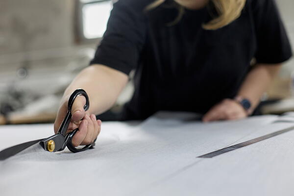 Image shows a person cutting paper on a table with scissors for the difference between fabric scissors and paper scissors.