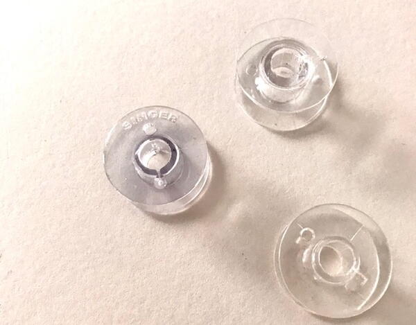 Image shows three sewing bobbins with and without thread.