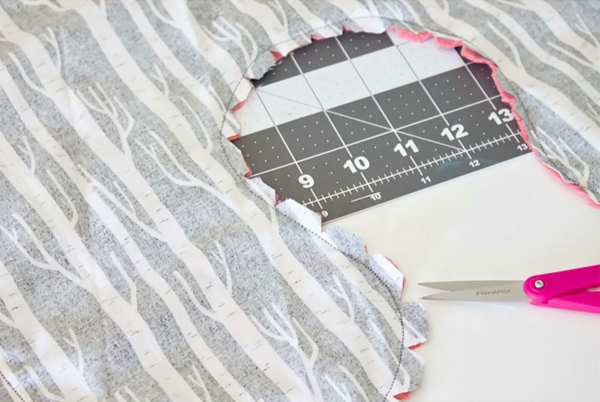 Image shows the cut DIY travel pillow fabric pieces pinned together and the curves clipped by scissors.